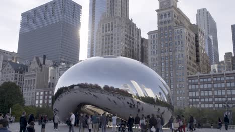 Daytime-shot-of-Chicago's-Cloud-Gate-sculpture-with-people-reflecting-in-its-surface,-set-against-city-buildings
