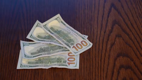 Hand-sliding-400-USD-Banknotes-into-frame-on-wooden-table