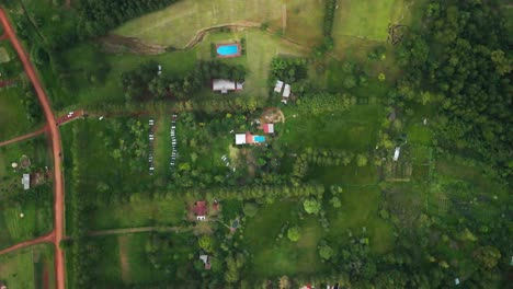 High-altitude-top-down-drone-Aerial-orbit-shot-of-the-property-farmhouse-in-the-middle-of-green-trees-and-farms