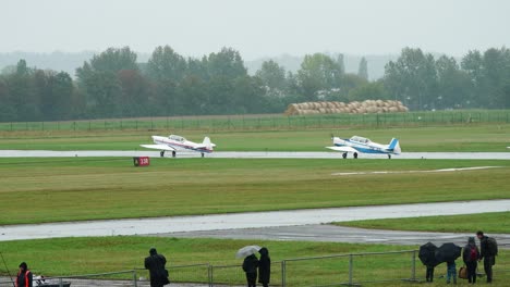 Old-sports-planes-drive-on-airport-runway-before-airshow-takeoff,-rainy-weather