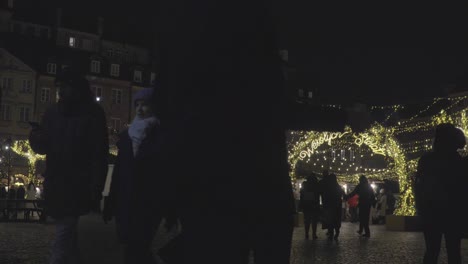 Menschen-Gehen-Nachts-Auf-Dem-Marktplatz-Der-Altstadt-Mit-Weihnachtsbäumen-Und-Beleuchtungsdekoration-In-Warschau,-Polen