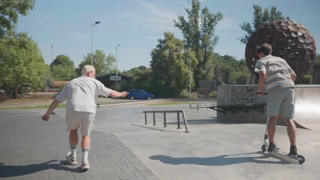 Man-use-action-camera-to-film-stunt-scooter-rider-doing-tricks-at-skatepark