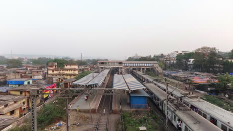 Trains-passing-by-suburban-railway-station-surrounded-with-slums