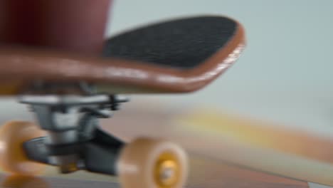 Eine-Makro-Detailaufnahme-In-Hyper-Nahaufnahme-Eines-Mini-Skateboards,-Winziger-Weißer-Räder,-Fahrendes-Griffbrett-Von-Rechts-Nach-Links,-Fingerrutschen-Vor-Und-Zurück,-Professionelle-Beleuchtung,-Statisches-Filmisches-4K-Video