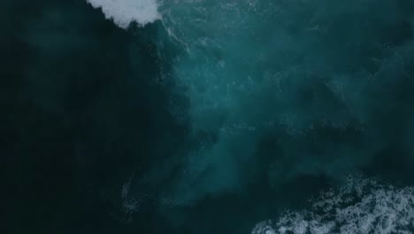 The-top-down-aerial-perspective-captures-the-artistic-beauty-of-giant-blue-ocean-waves-crashing-and-creating-a-foam-covered-whitewash-background