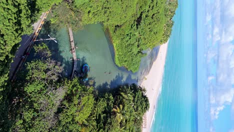 Vertical-View-Of-People-Swim-At-Los-Patos-River-By-The-Beach-With-Blue-Seascape-In-Summer-In-Barahona,-Dominican-Republic
