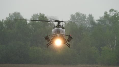Helicóptero-Militar-Con-Foco-Brillante-Realiza-Maniobras-De-Aterrizaje,-Clima-Lluvioso