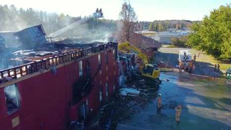 Zerstörtes-Gebäudepanorama-Nach-Waldbrand-Mit-Baggern-Und-Feuerwehrmann-Drohnen-Luftaufnahme