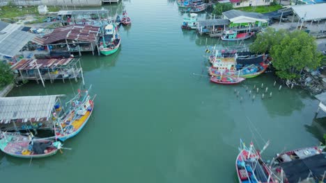 Drone-flies-over-this-estuarine-river-revealing-this-fishing-village,-boats-and-people-swimming-as-seen-from-above,-Bang-Pu-Fishing-Village,-Sam-Roi-Yot-National-Park,-Prachuap-Khiri-Khan,-Thailand