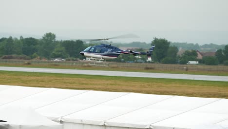 Bell-206-helicopter-fly-in-low-altitude-while-Antonov-an-2-plane-taxiing