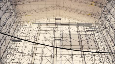 tilt-up-wide-angle-shot-of-a-large-tent-structure-held-up-by-scaffold-covering-an-old-ship