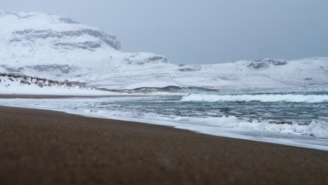 Stormy-cold-winter-waves,-snowing-and-heavy-wind-at-Norway-Ervik-beach,-vestkapp