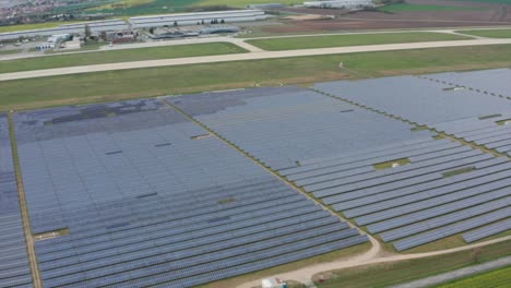 Huge-photovoltaic-solar-farm-by-the-airport,-aerial-view