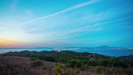 Timelapse-of-Streaked-sunset-skies-over-rolling-hills-and-distant-coastline-on-a-beautiful-day