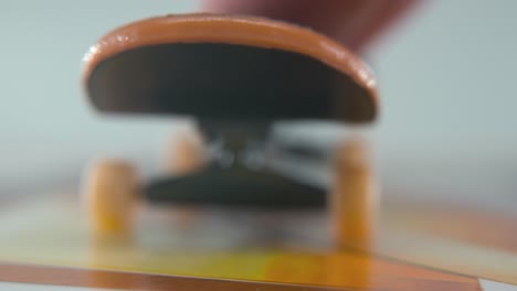 A-close-up-macro-detailed-shot-of-a-mini-skateboard,-tiny-white-wheels,-riding-fingerboard,-finger-slide-back-and-forward-in-front-of-the-camera,-professional-lighting,-static-cinematic-4K-video
