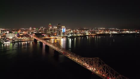 Louisville,-Kentucky-skyline-at-night-with-bridge-in-foreground-with-stable-drone-video