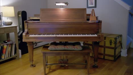 A-vintage-wooden-piano-in-a-living-room-with-an-antique-mechanical-metronome-swinging-at-60bpm-on-the-right,-a-guitar-case-and-rustic-trunk-in-the-back