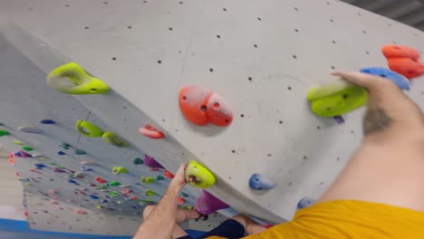 POV-shot-of-a-man-with-tattoos-climbing-in-a-bouldering-gym