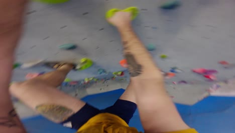 POV-shot-of-a-climber-man-with-tattoos-climbing-in-a-bouldering-gym-an-overhang-wall