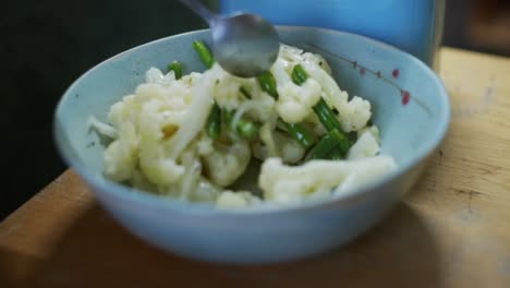 Freshly-boiled-and-fried-cauliflower-and-green-beans-being-stirred-in-bowl,-filmed-as-close-up-slow-motion-shot-with-slider-style-movement