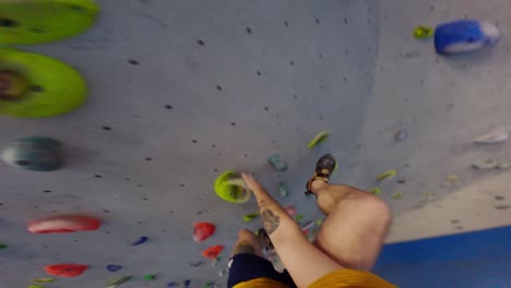 Climber-training-on-an-artificial-climbing-wall,-first-person-shot