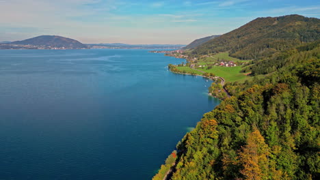 Aerial-panning-shot-of-Attersee-in-Austria,-showcasing-autumn-foliage-and-clear-blue-waters