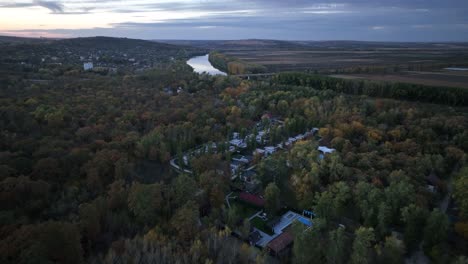 approaching-a-drone-to-a-town-located-next-to-the-Dniester-River,-hidden-in-the-forest-around-the-trees