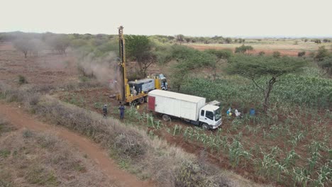Engineers-supervising-drilling-borehole-well-on-African-farmland-in-Kenya,-aerial