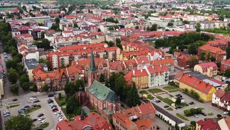 Beautiful-rooftops-and-church-tower-of-Elk-city,-aerial-view