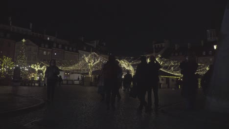 La-Gente-Camina-En-La-Plaza-Del-Mercado-Del-Casco-Antiguo-Con-árboles-De-Navidad-Iluminando-La-Decoración-En-Varsovia,-Polonia,-Durante-La-Noche