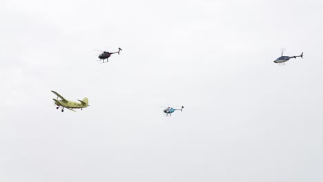 Helicopters-and-old-agricultural-aircraft-fly-in-bright-sky-during-airshow