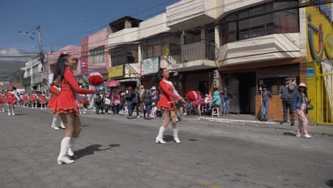 Majorettes-red-costume-twirl-batons-towns-day-of-Independence-parade-slo-mo
