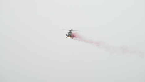 Multi-purpose-helicopter-fly-with-spotlight-on-and-emit-smoke-during-airshow