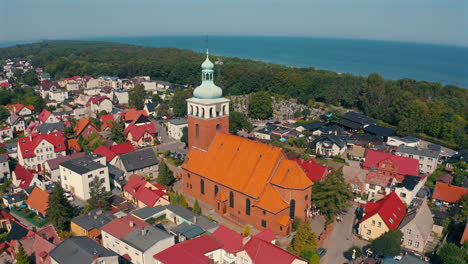 Aerial-view-of-church-in-Jastarnia,-Poland-with-baltic-sea-in-the-background