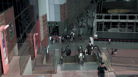 Toma-En-Cámara-Lenta-De-Personas-Caminando-Y-Subiendo-Escaleras-Mecánicas-En-La-Estación-De-Kyoto-En-Japón