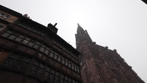 View-onto-the-Strasbourg-Cathedral-against-a-cloudy-sky-backdrop,-towers-rise-proudly,-flanking-the-entrance-and-providing-a-glimpse-of-the-splendor-that-lies-within