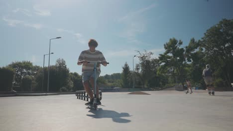 Male-on-stunt-scooter-do-freestyle-trick-session-at-skatepark,-summer-day