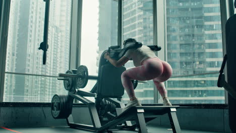 Sexy-girl-in-tight-yoga-pants-uses-lever-squat-machine-to-train-her-buttocks