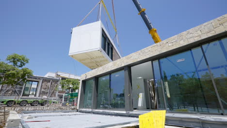 Heavy-crane-lifting-block-of-modular-home,-view-from-bellow
