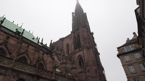 View-onto-the-Strasbourg-Cathedral-against-a-cloudy-sky-backdrop,-the-tower-rises-proudly,-flanking-the-entrance-and-providing-a-glimpse-of-the-splendor-that-lies-within