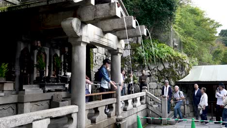 Turista-Recogiendo-Agua-De-La-Cascada-Otowa-no-taki-En-El-Templo-Kiyomizu