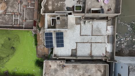 Aerial-top-view-shot-of-old-buildings-with-solar-panel-beside-a-pond-in-Pakistan