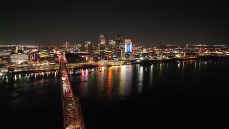 Louisville,-Kentucky-skyline-at-night-with-bridge-in-foreground-with-drone-video-moving-in-up-high