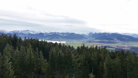 Establish-View-of-swiss-town-Einsiedeln-and-lake-Sihlsee,-snowy-mountains