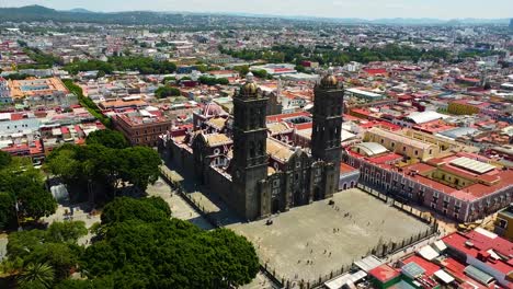 Aerial-approaching-shot-of-famous-Cathedral-de-Puebla-City-with-visiting-tourist-on-square-at-sunny-day,-Mexico