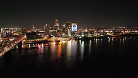 Skyline-Von-Louisville,-Kentucky-Bei-Nacht-Mit-Brücke-Im-Vordergrund-Und-Kreisendem-Drohnenvideo