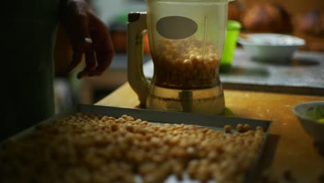 Chickpeas-spooned-out-of-baking-tray-and-placed-into-blender,-filmed-as-close-up-slow-motion-shot