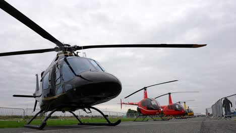 Black-utility-helicopter-parked-during-airshow-exhibition-behind-fence