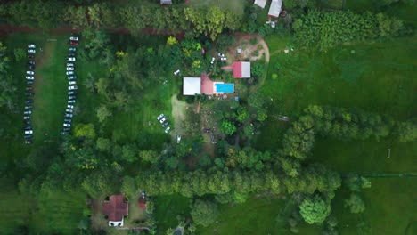 top-down-Zoom-out-drone-shot-of-the-farmhouse-with-visitors-cars-parked-at-a-farmhouse