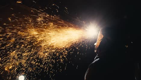 closeup-tight-shot-of-a-man-welding-metal-together-in-a-dark-room-with-sparks-flying-everywhere